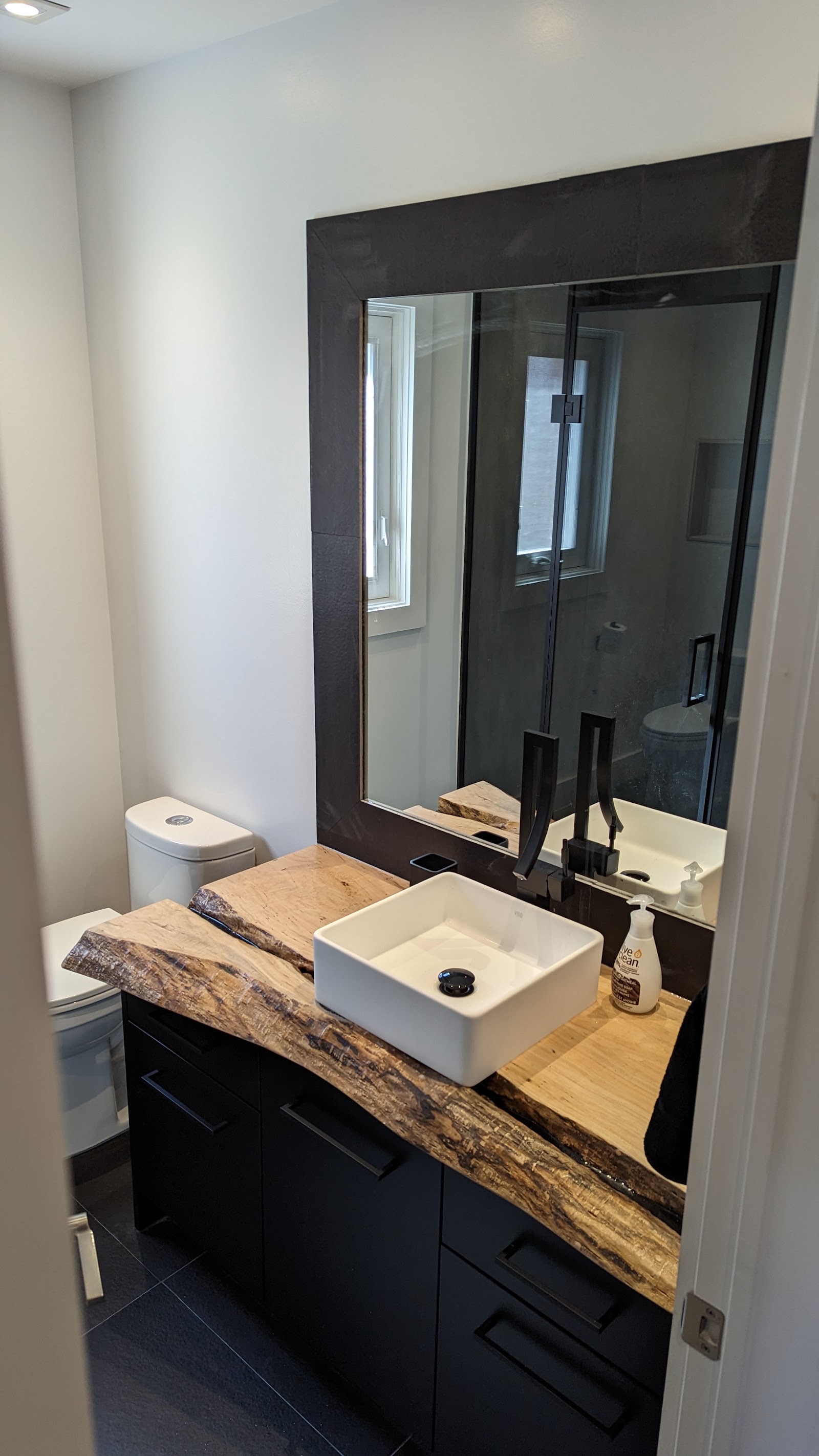 Finished bathroom vanity, mirror, faucet, and glass shower detail